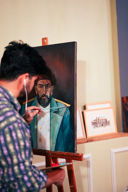 Man in Headphones Painting on Easel