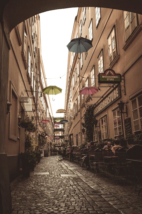 Cobblestone Old Town Alley with Umbrellas Hanging between Buildings for Decoration 