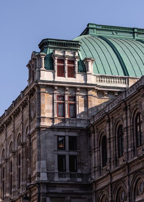 Free Low-angle view of a classic European building with intricate architecture and a green roof. Stock Photo