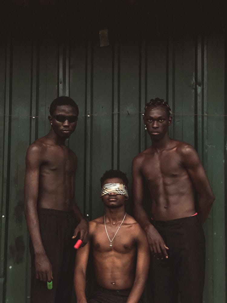 Shirtless Men Standing By A Man With A Blindfold On