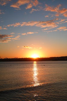 Capture of a breathtaking sunset over a calm lake with vibrant skies and serene water reflection.