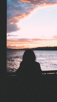 A serene silhouette of a woman overlooking the ocean during sunset, capturing a peaceful moment.. serene, silhouette, woman