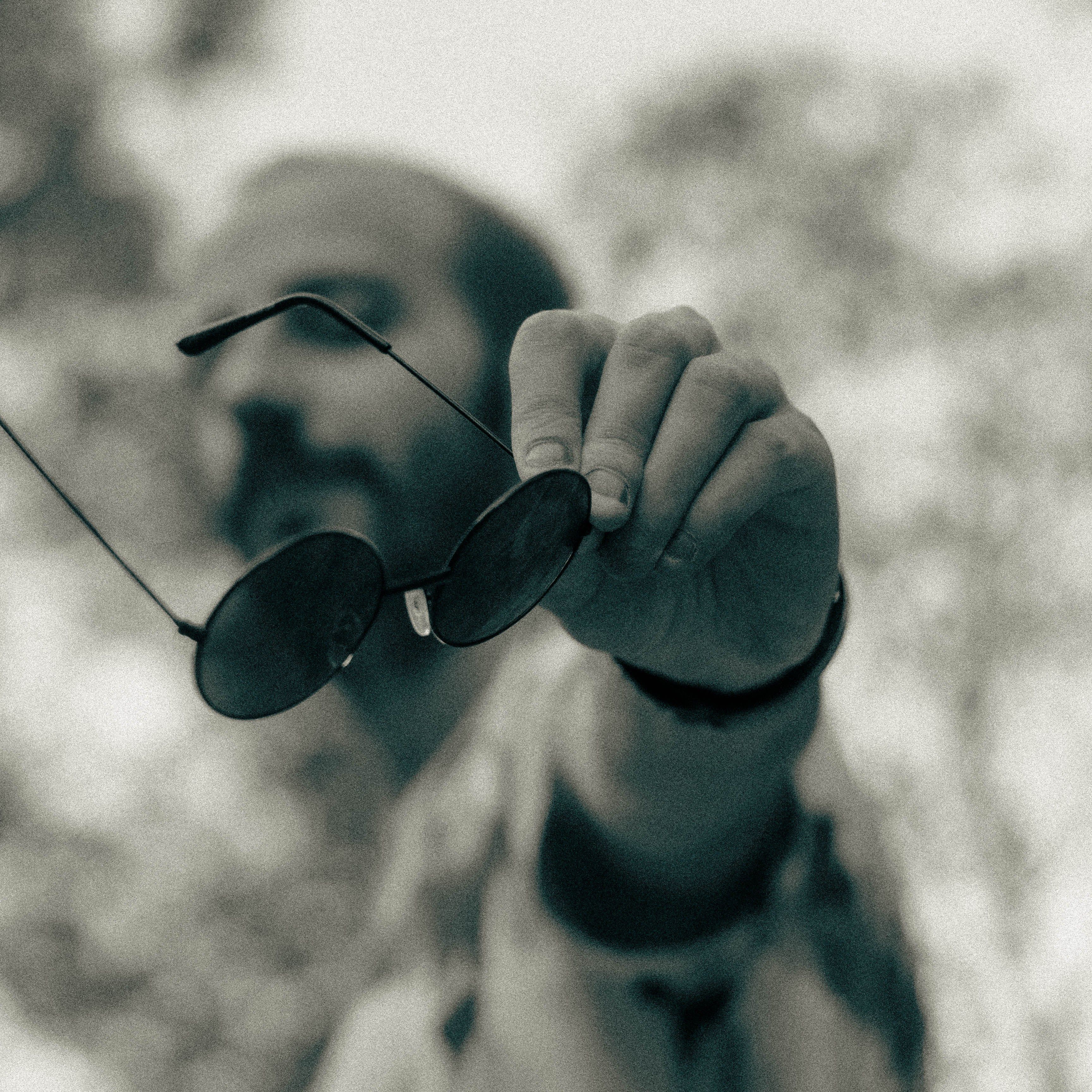 Grayscale Photo of a Man Holding Sunglasses