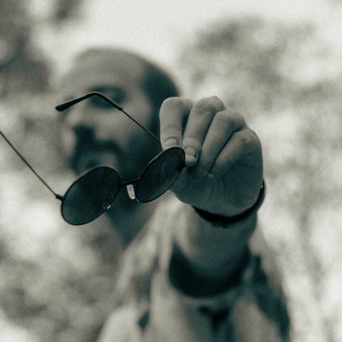 Free A stylish monochrome photograph depicting a person holding sunglasses with a blurred background. Stock Photo
