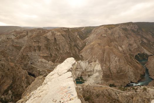 Breathtaking aerial shot of rugged brown mountains and deep valleys under a cloudy sky.