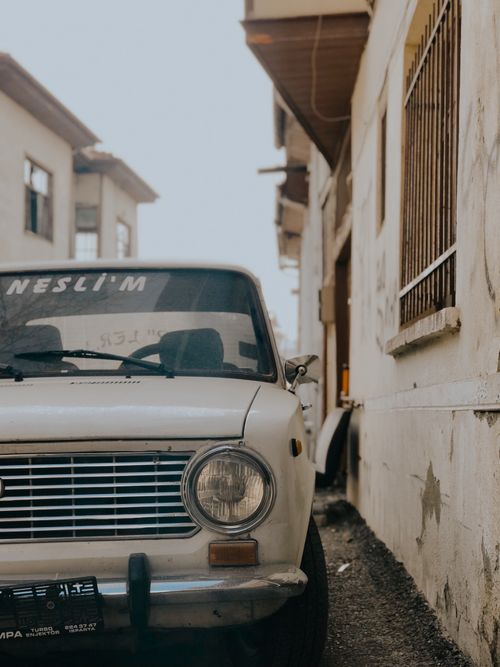 Free A retro car parked in a narrow alleyway beside weathered buildings, creating a nostalgic feel. Stock Photo