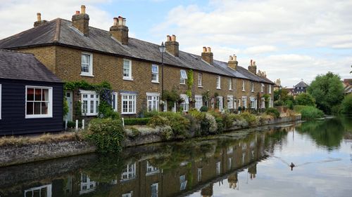 Free Traditional English cottages by a serene canal reflecting the tranquil countryside. Stock Photo
