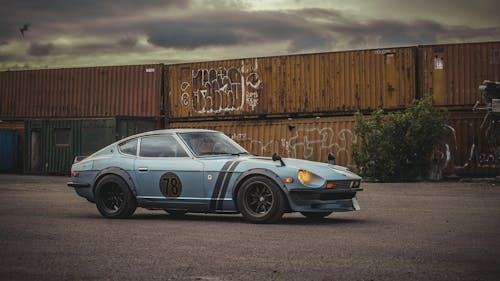 Vintage Sports Car Parked Near Cargo Containers