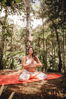 Pregnant woman meditating in a serene forest setting on a yoga mat, embracing nature with calmness.