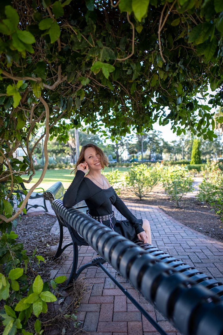 A Woman Sitting On Bench While Smiling