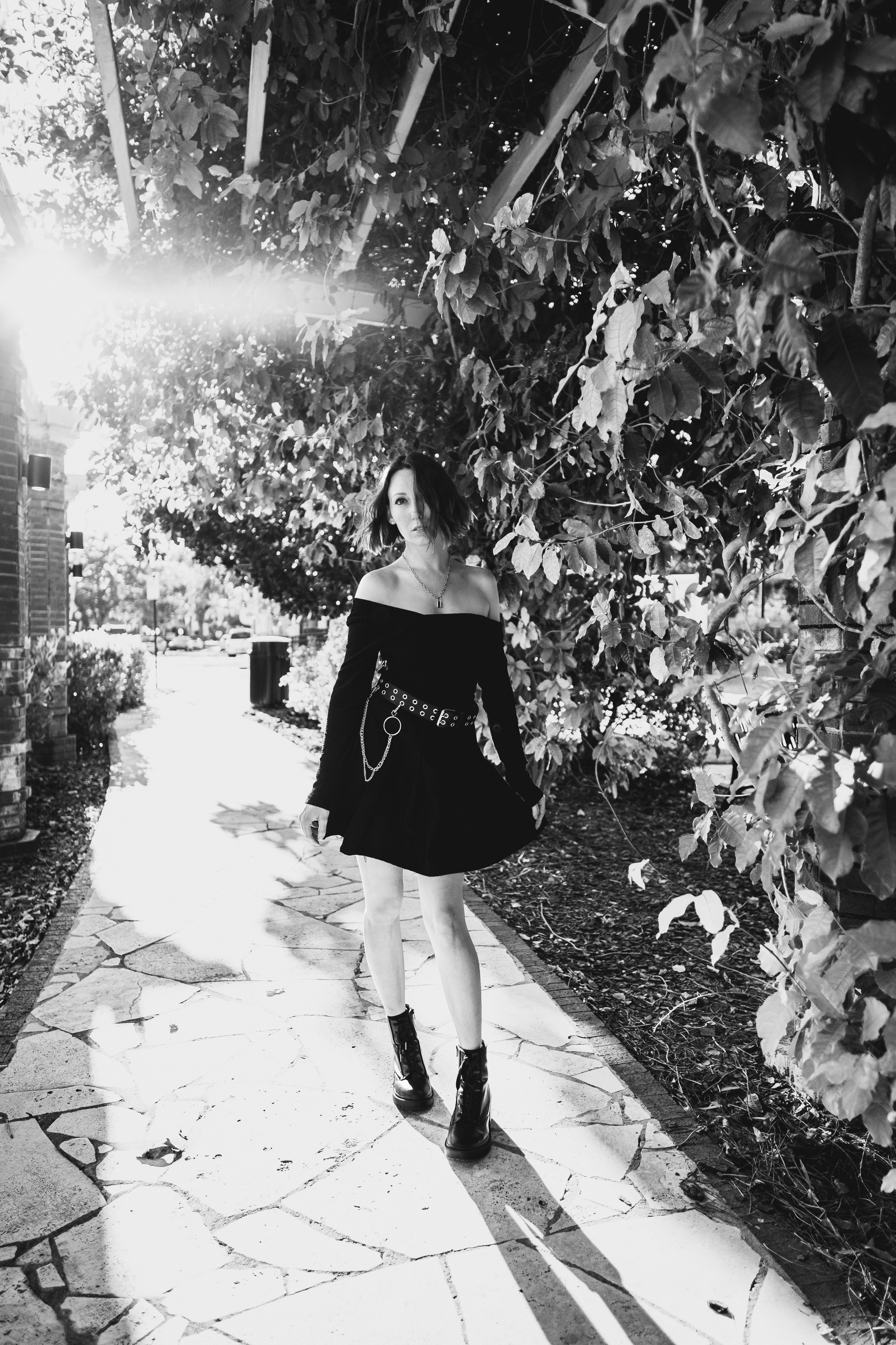 A Grayscale Photo of a Woman in Black Dress Standing on the Street ...