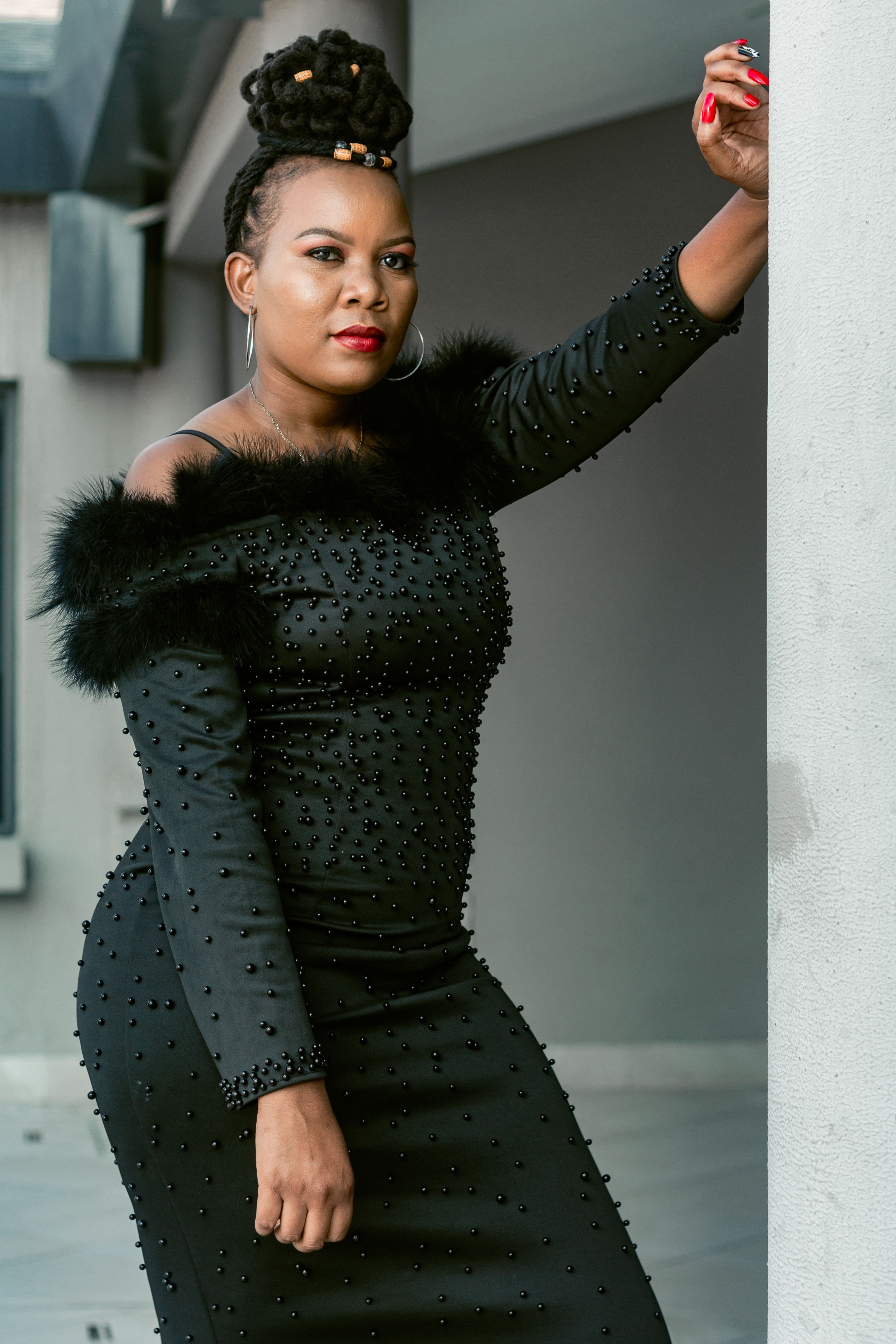 A stylish woman in a beaded black dress poses confidently, exuding elegance and fashion.