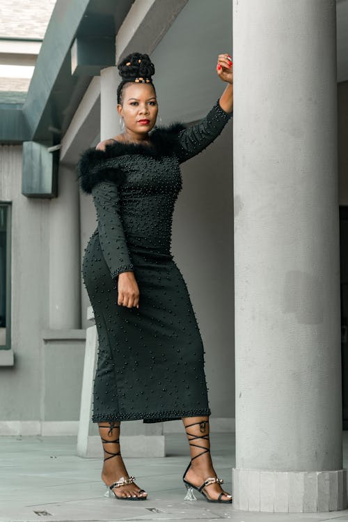 Woman in Black Long Sleeves Dress Standing Beside a Pillar while Posing at the Camera
