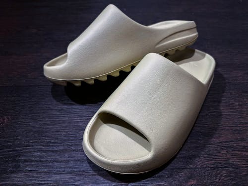 Gray Yeezy Slides on a Wooden Surface