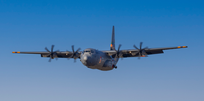 Military aircraft flying with a clear blue sky backdrop, showcasing strength and precision.