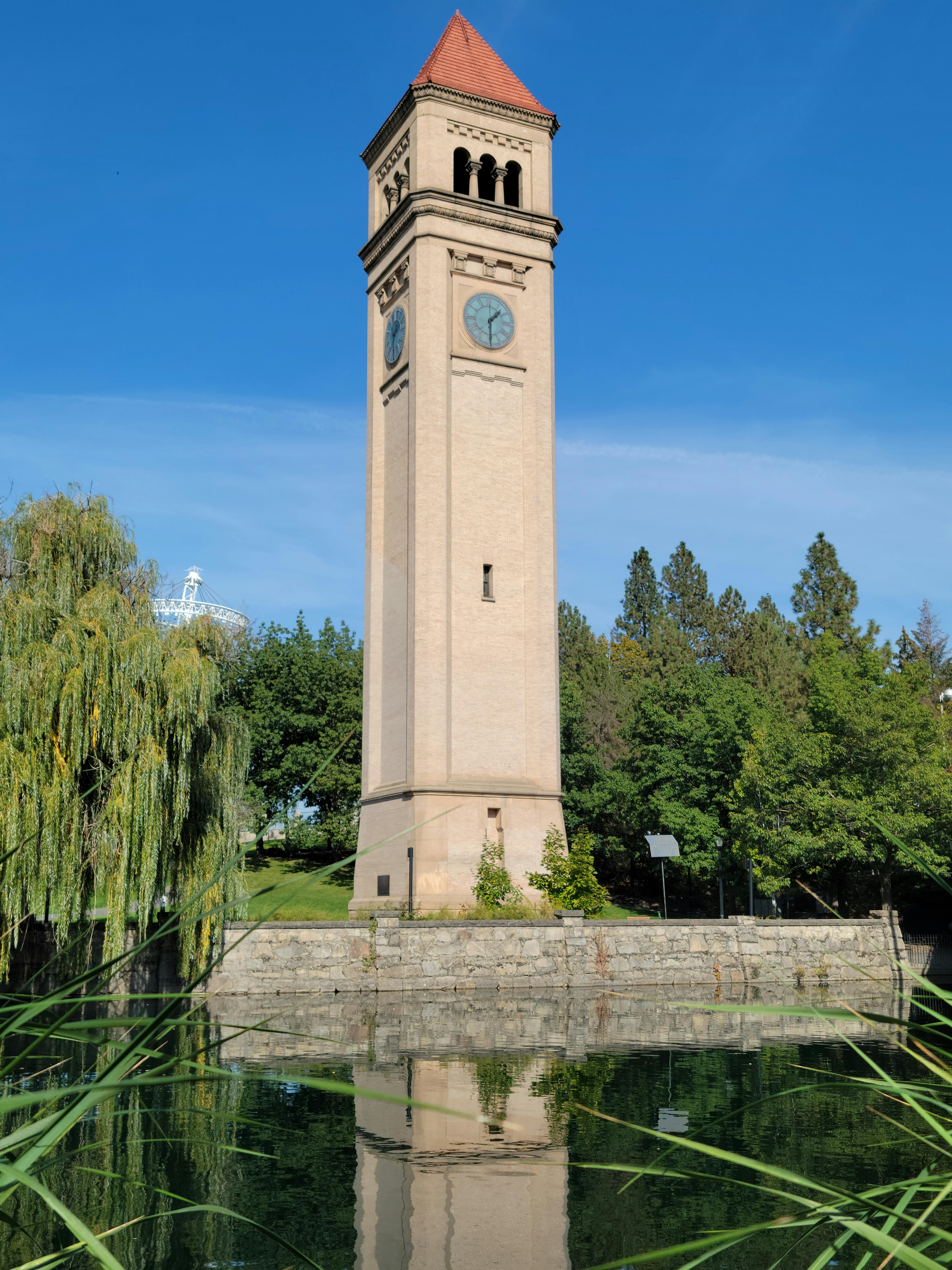 A Clock Tower Near Green trees Beside a River · Free Stock Photo