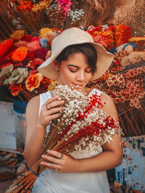 Free A woman in Brasília enjoys a fragrant bouquet at a colorful flower shop, surrounded by vibrant blossoms. Stock Photo