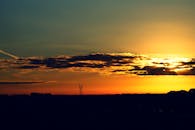 日落时分，宁静的景色中，树木和输电塔的轮廓映衬着五彩缤纷的天空