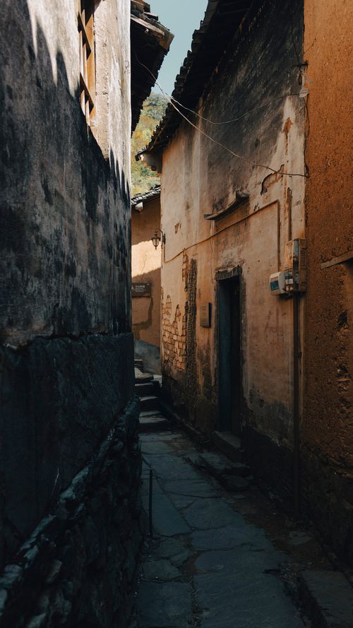 Free Explore the texture-rich, narrow alleyway with rustic buildings and historical charm. Stock Photo