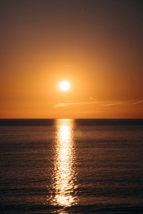 Free Breathtaking sunset over calm ocean, capturing the warm glow and tranquil horizon. Stock Photo