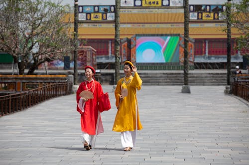 Women in Yellow and Red Ao Dai Dresses Walking on the Street