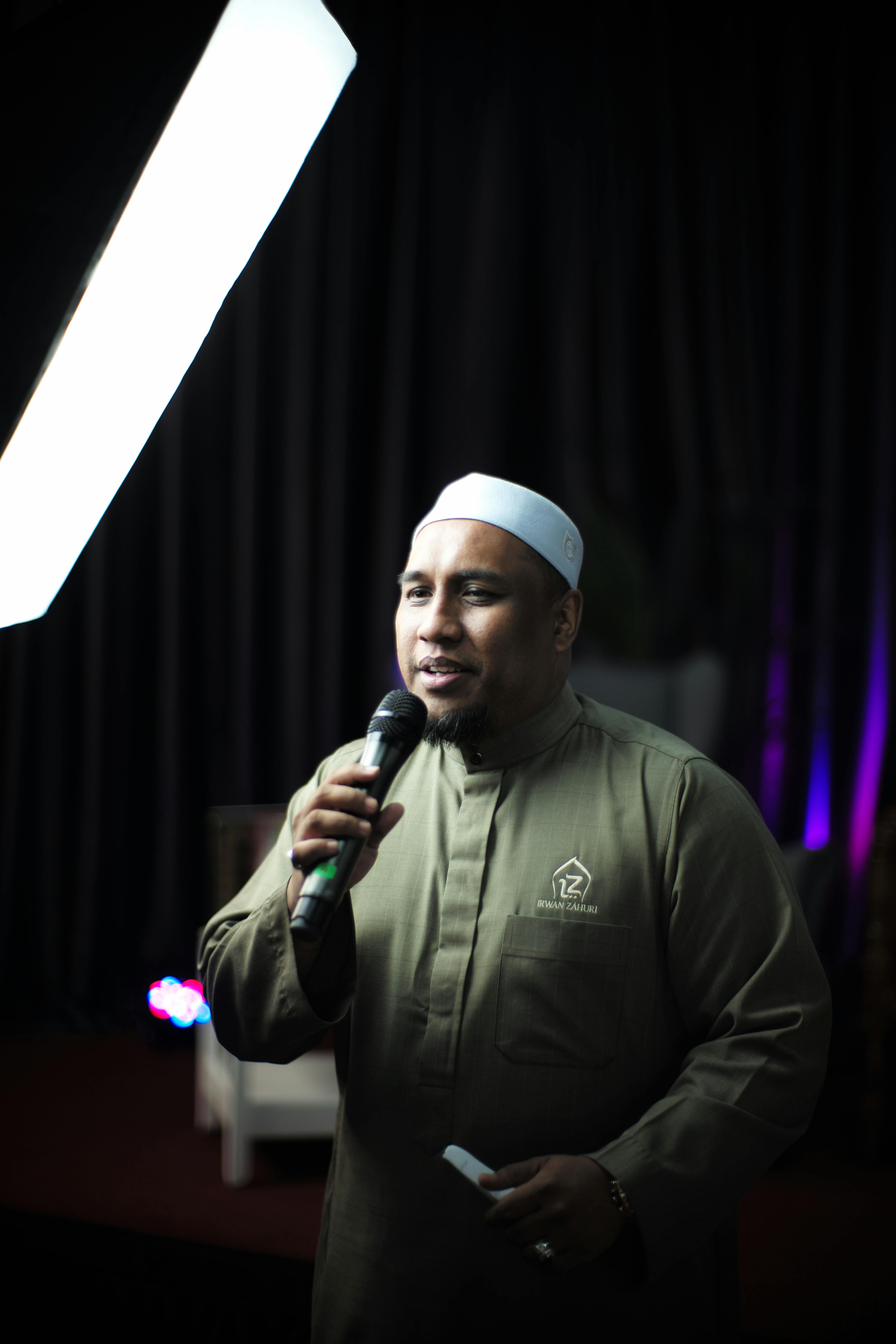 A person singing joyfully under studio lights with a microphone, showcasing traditional attire.