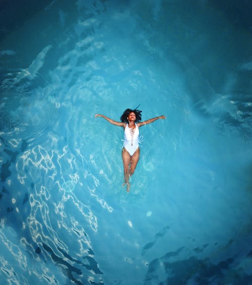 Женщина в белом монокини плавает на водоеме