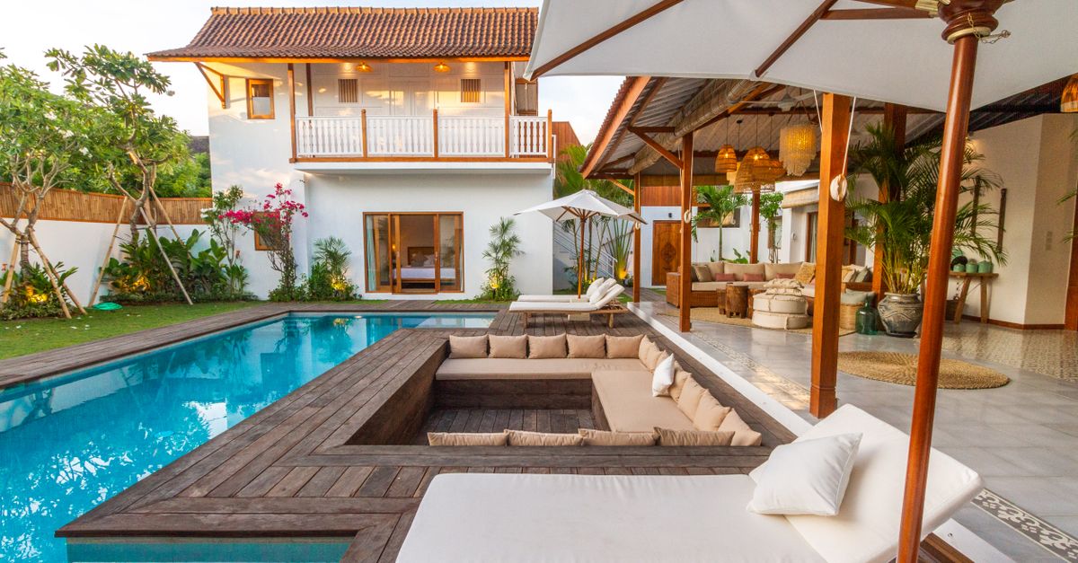 Beautiful modern villa featuring a pool, wooden deck, and lush greenery.