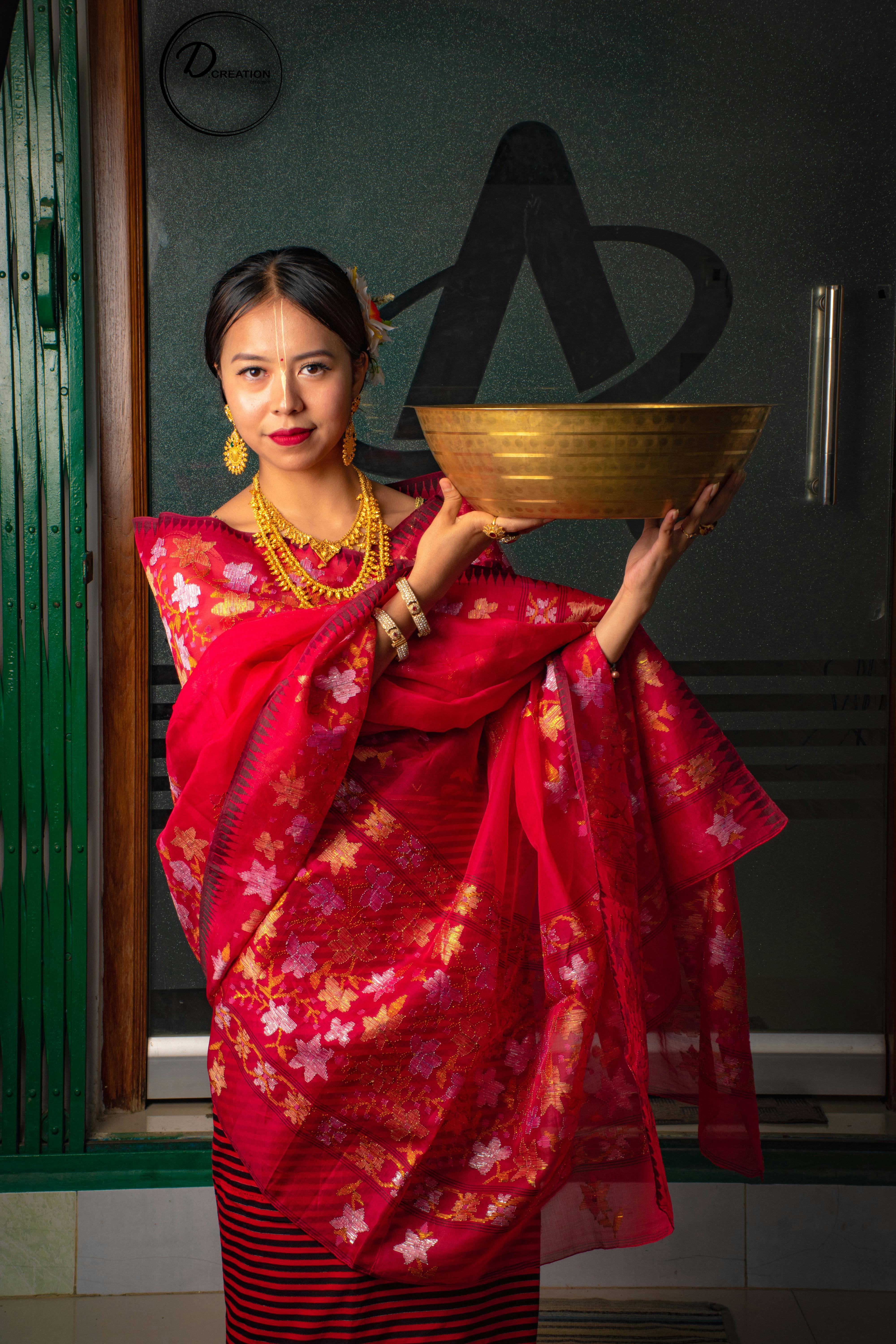 Portrait of a young woman in traditional Indian attire holding a brass bowl indoors, showcasing cultural heritage.