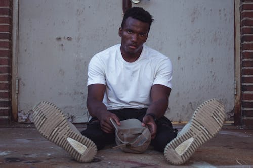 Man Sitting on Floor While Holding Cap