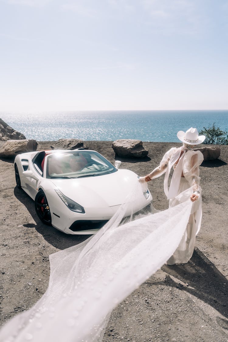 Woman With Tulle Posing On Beach Near Sport Car