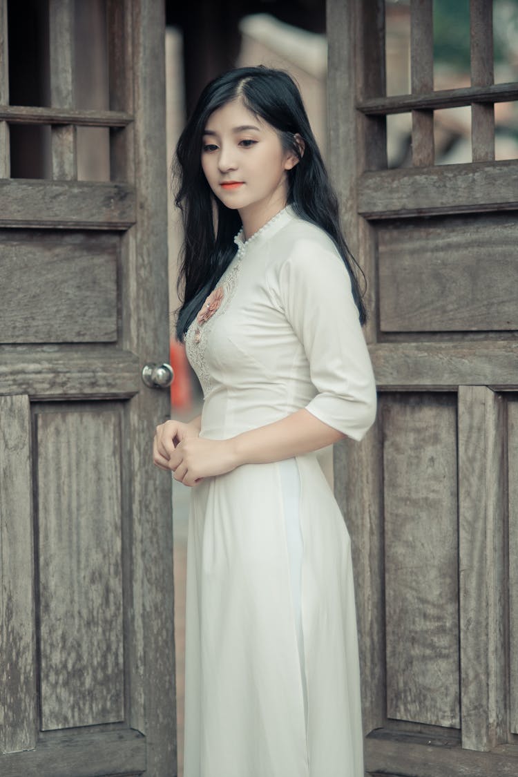 Woman Wearing White Dress In Middle Of Two Brown Wooden Doors