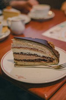 Appetizing chocolate layered cake slice with fork on plate, perfect for dessert lovers.