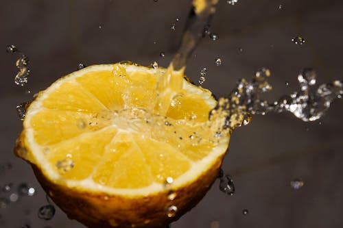 Close-up Photography of Water Poured on Slice of Yellow Lemon