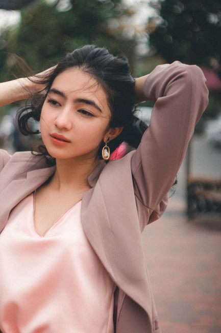 Stylish woman in a brown blazer with flowing hair captured in an urban area.