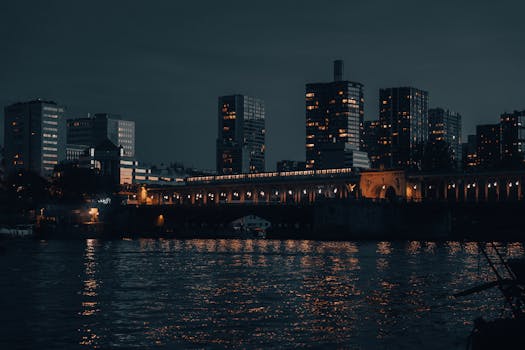 Nighttime view of Paris skyline with illuminated buildings reflected on the river.