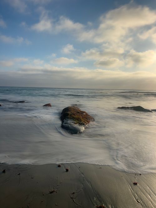 Free Serene view of San Diego's coastline with gentle waves and a rocky shoreline during sunset. Stock Photo