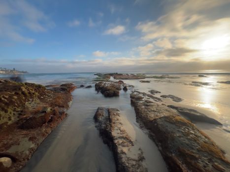 Mesmerizing view of rocky seashore under a vibrant sky during sunset, capturing nature's beauty.