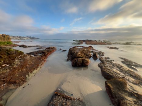 Serene coastal view with rocks and a cloudy sky at a tranquil beach.