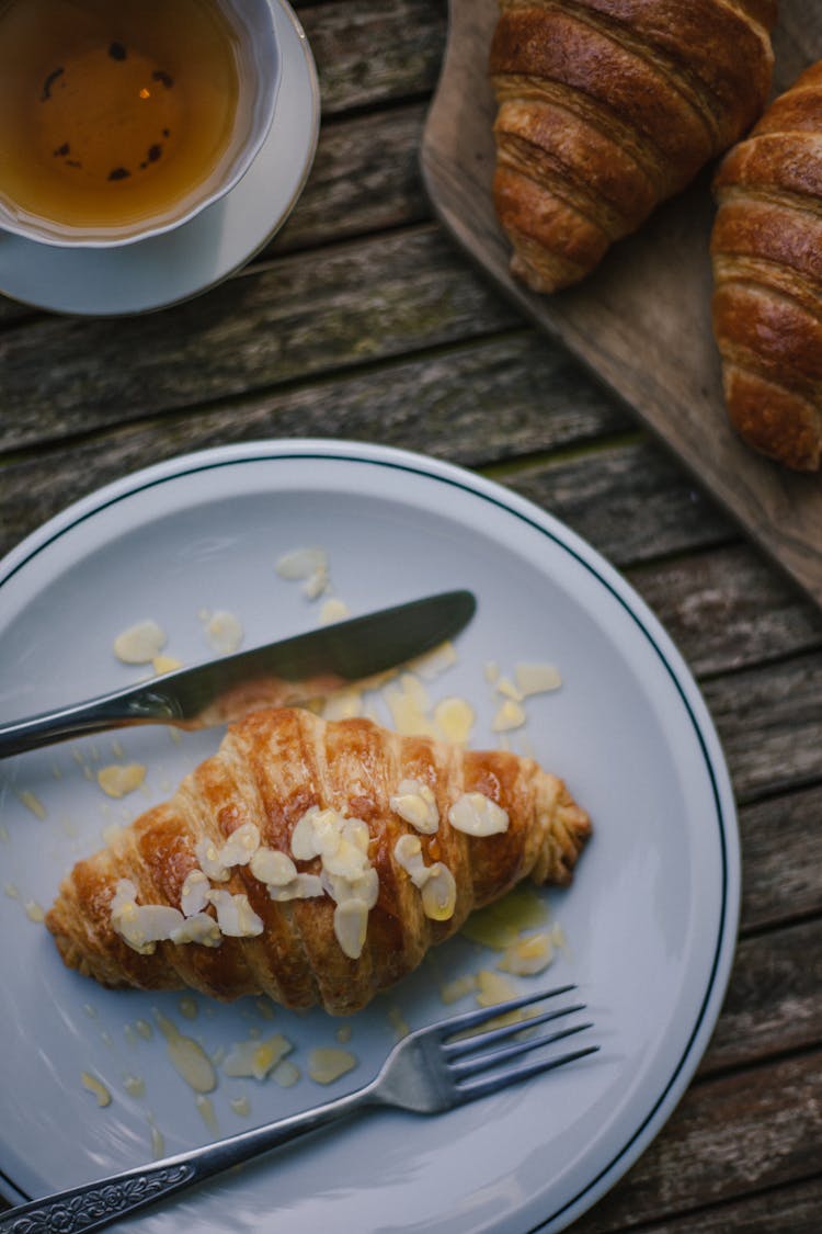 Almond Croissant And Tea On Wooden Table