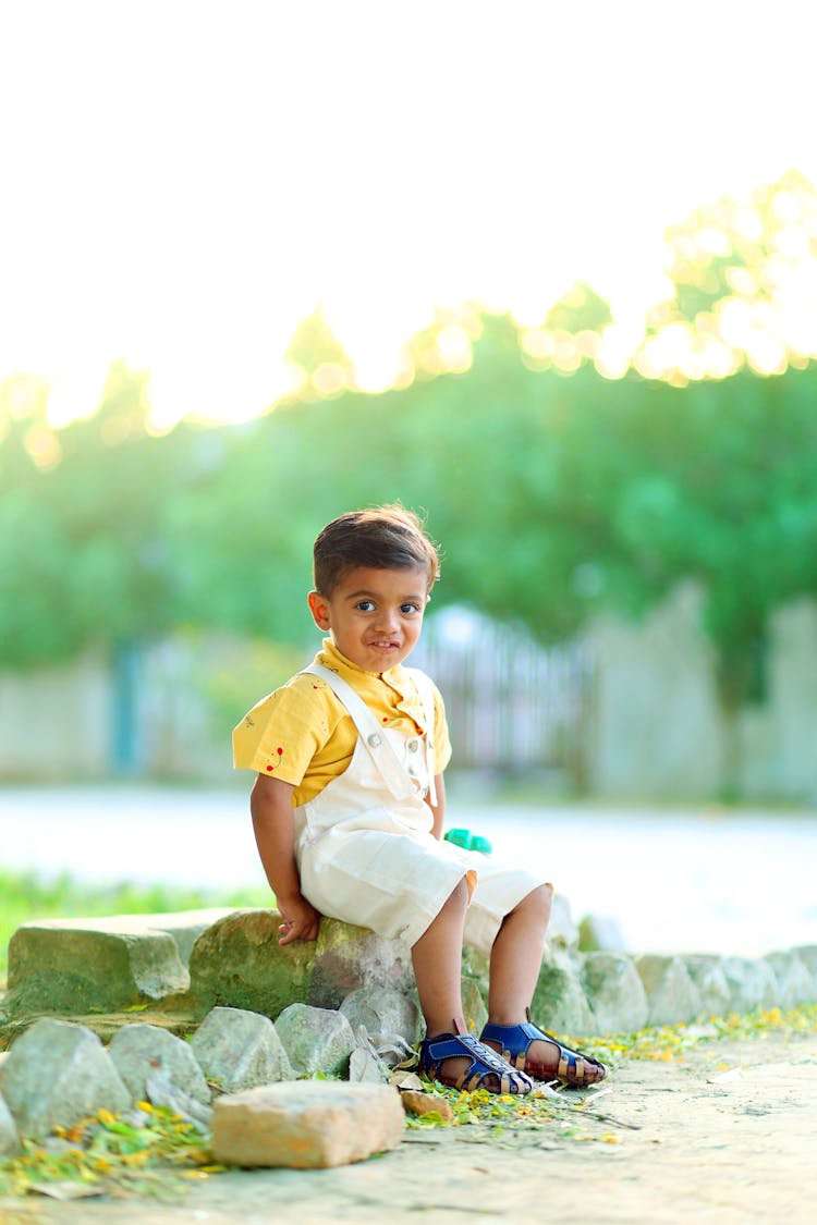 Little Boy Sitting On The Rock