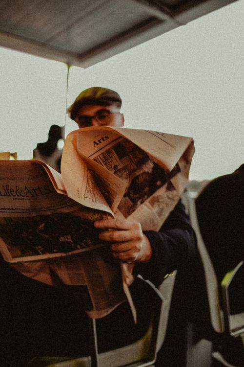 Free A man in a cap reading a newspaper indoors, creating a cozy and thoughtful atmosphere. Stock Photo