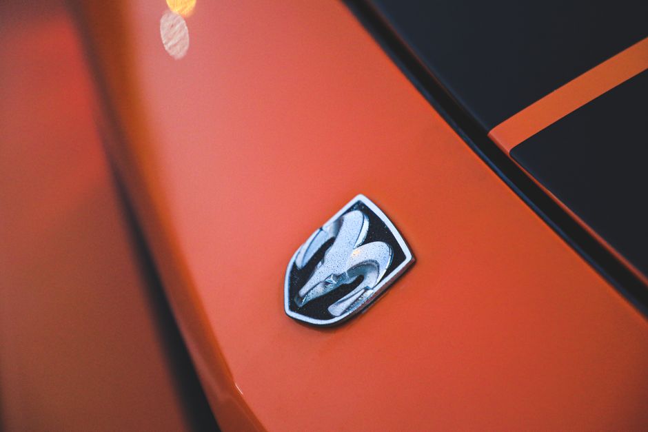 Ride with the Dodge Brand at Barrett-Jackson West Palm Beach 2 Detailed view of the iconic Dodge emblem on a vibrant orange muscle car in Dubai. | BocaVibe