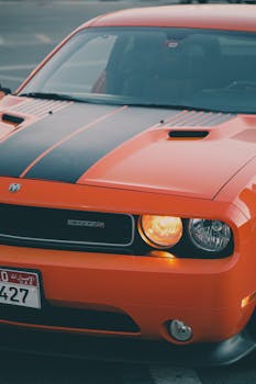Close-up shot of an orange Dodge Challenger on a Dubai street, showcasing luxury and power.