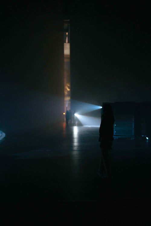 Free A mysterious silhouette stands in a dimly lit indoor area with scattered beam lights at night. Stock Photo