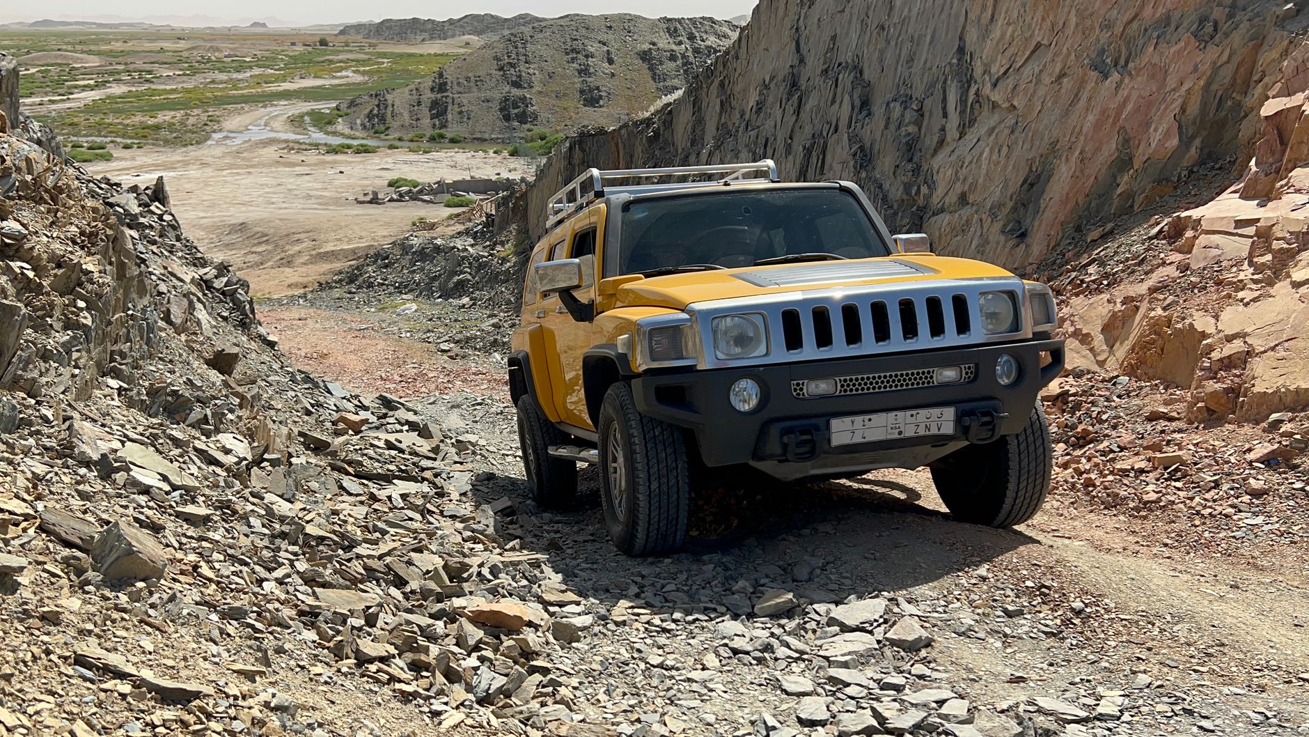 Off-road 4x4 SUV descending a rugged rocky mountain trail in remote backcountry terrain