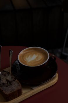A cozy setup with a cup of coffee and bread on a wooden tray in a dimly lit cafe.
