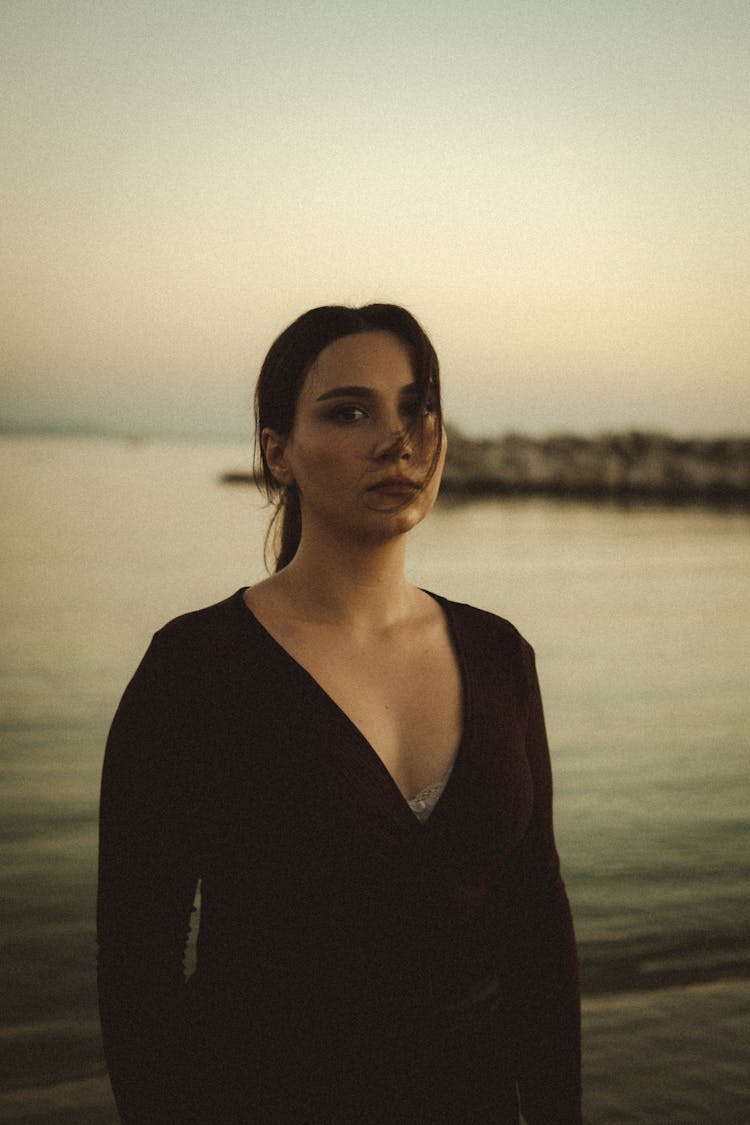 Woman Posing Near Water On Sunset