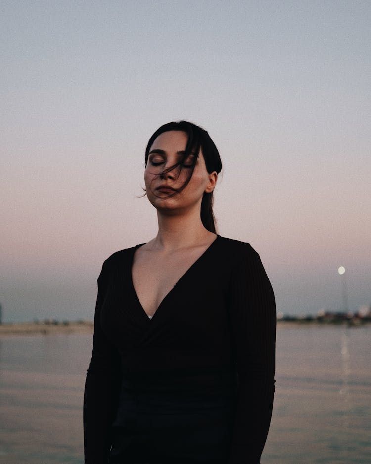 Woman In Black Dress Near Sea On Sunset