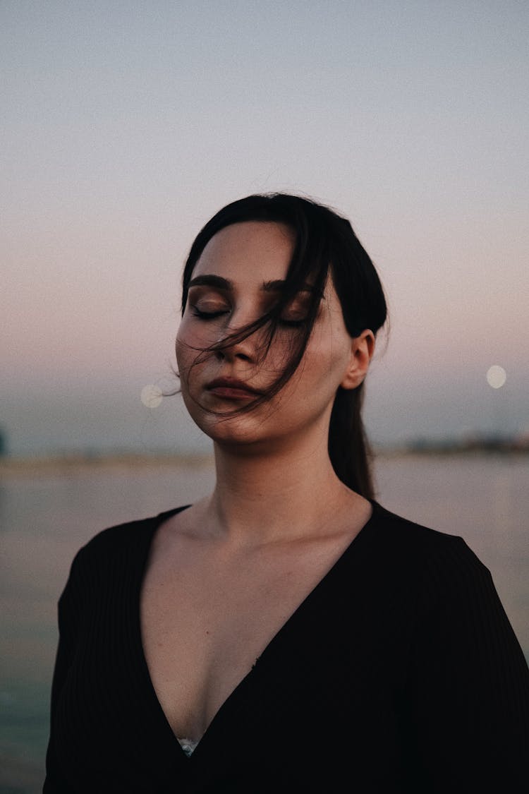 Young Woman Posing Near Water On Sunset